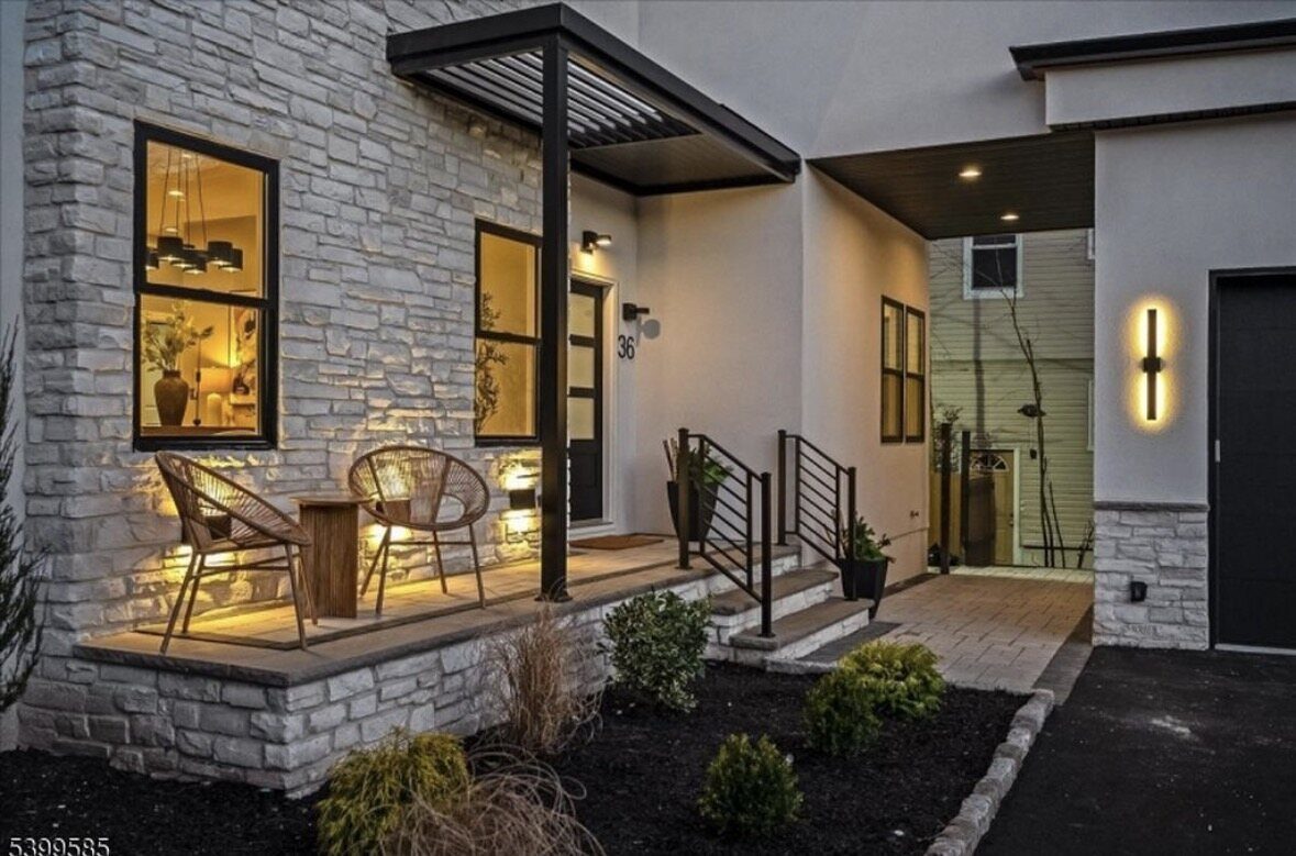 Black horizontal bar step railing at a modern front porch with a stone facade